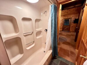 Une salle de bain avec une baignoire, une douche et une porte en bois.