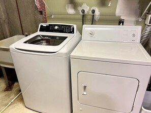 A laundry area with two white washing machines, a sink, and a wall with exposed pipes. - Fantastic Lakefront Wooden Cabin Settled Between Trees in Stratton, Vermont (Stratton)