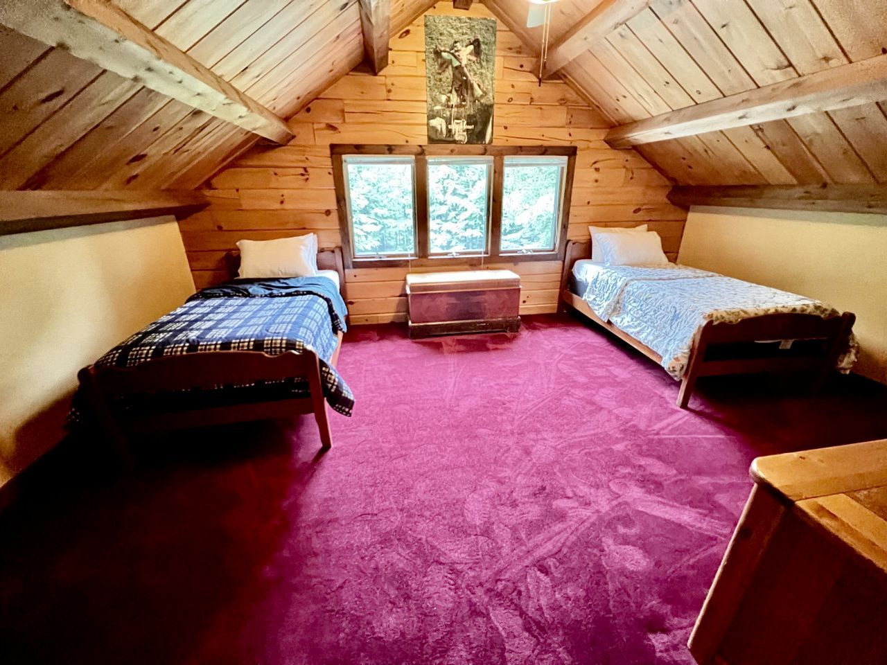 A cabin with two beds, a central heater, and a large window.