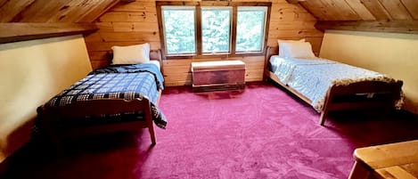 A cabin with two beds, a central heater, and a large window.
