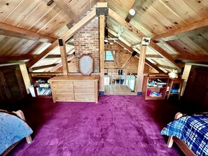 Une chambre de style « loft », avec un tapis violet, des meubles en bois et un mur en briques.