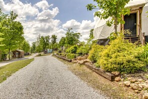 A gravel driveway leading to a building with a covered porch, surrounded by greenery and trees. - Riverfront Dome with Outdoor Living and Sunset Views in Alabama (Rogersville)