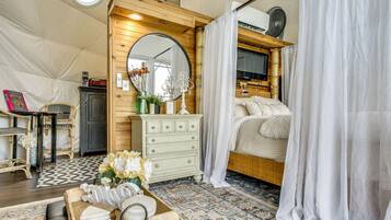 A cozy bedroom with a bed, a dresser, a mirror, and a window with curtains.
