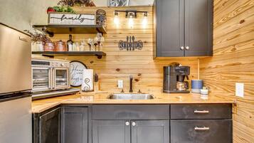 A kitchen with wooden cabinetry, a stainless steel sink, a coffee maker, and various kitchen utensils.