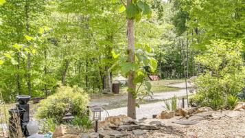 A garden area with a gravel path, a stone wall, and various plants.