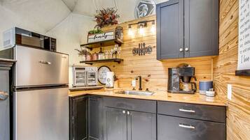 A compact kitchen with a refrigerator, a coffee maker, and a toaster.