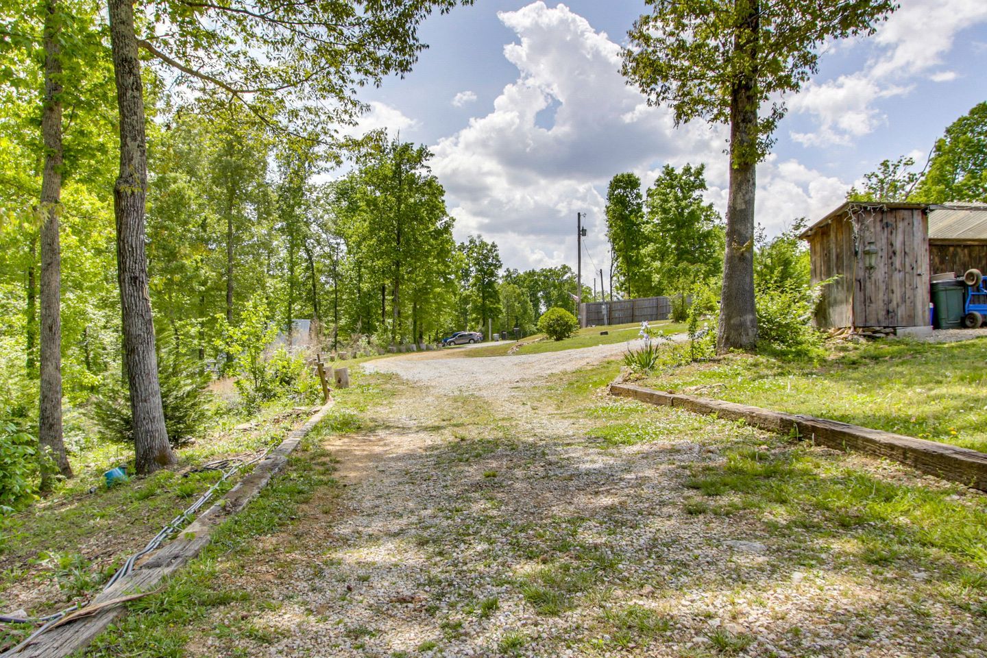 A gravel path leading to a wooden structure with a metal fence and trees.
