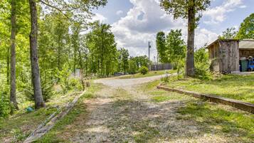 A gravel path leading to a wooden structure with a metal fence and trees.
