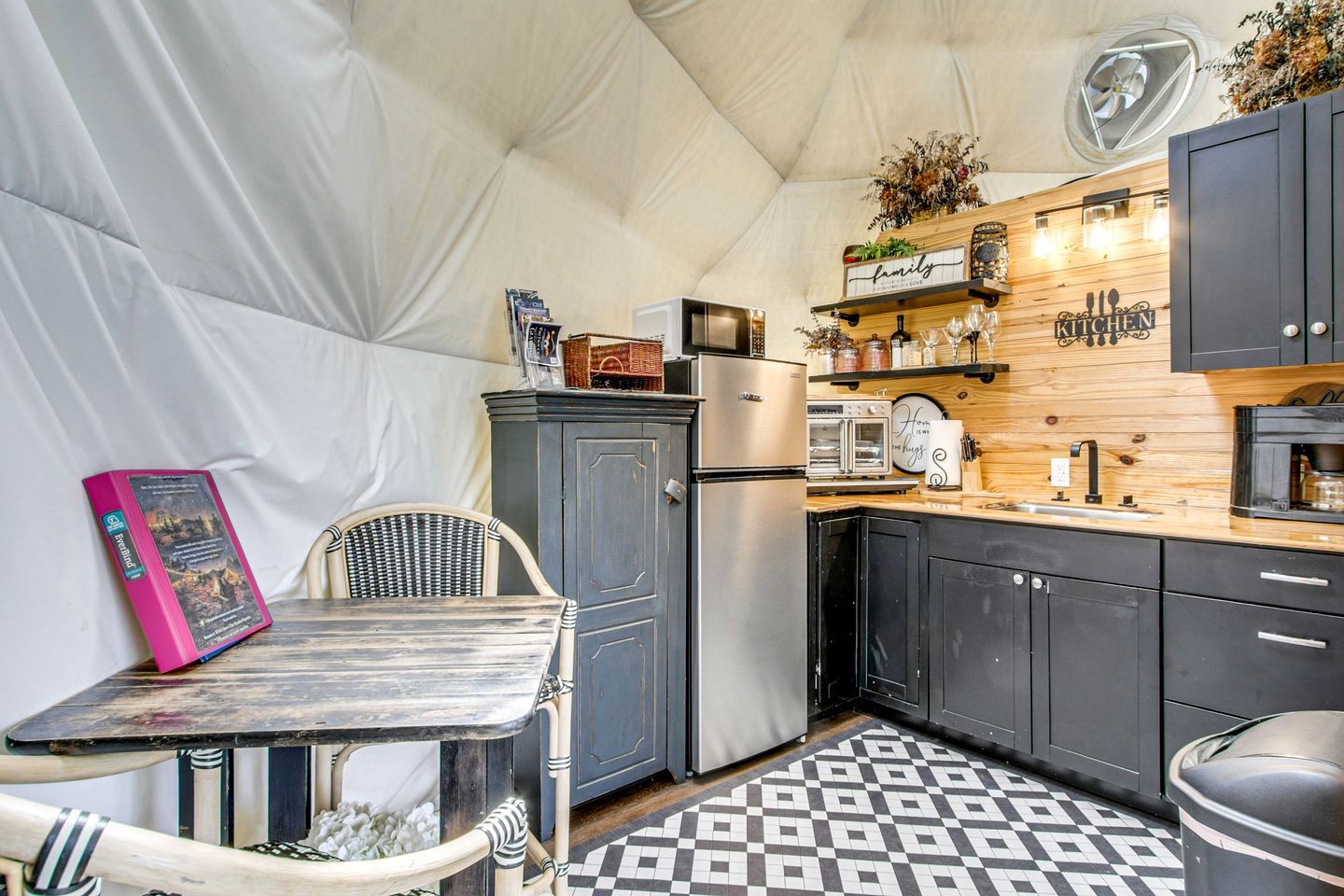 A compact kitchen with a refrigerator, microwave, and a coffee machine.