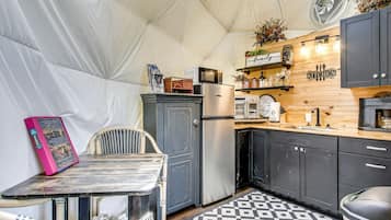 A compact kitchen with a refrigerator, microwave, and a coffee machine.