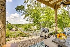 A hammock under a wooden pergola with a view of a green landscape and a house in the background. - Riverfront Dome with Outdoor Living and Sunset Views in Alabama (Rogersville)