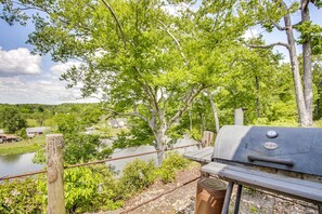 Une vue sur la rivière, avec un barbecue et une clôture en bois.