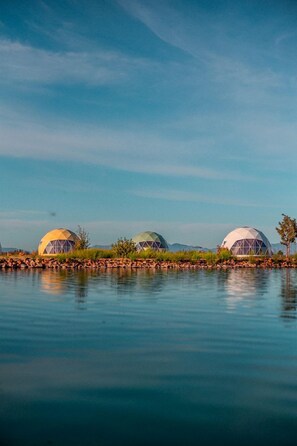 Three dome-shaped structures by a calm body of water. - Amazing Dome with the Greatest Desert Views Ever in Willcox, Arizona (Wilcox)