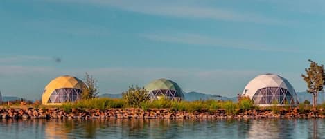 Three dome-shaped structures by a calm body of water.