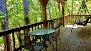 A wooden deck with a table and chairs, surrounded by trees. - Rustic Cabin with Indoor Bath Spa and Deck in Arkansas (Eureka Springs)