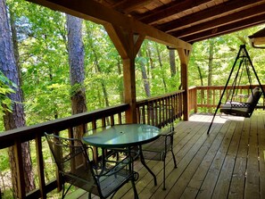 A wooden deck with a table and chairs, surrounded by trees. - Rustic Cabin with Indoor Bath Spa and Deck in Arkansas (Eureka Springs)
