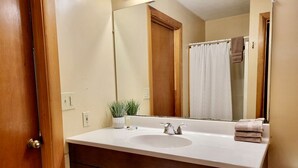 A bathroom with a sink, mirror, wooden cabinets, and a towel rack. - Rustic Cabin with Indoor Bath Spa and Deck in Arkansas (Eureka Springs)