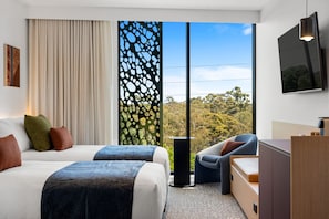 A modern hotel room with two beds, a large window with a view of trees, a TV, and a desk. - Hackney Hotel (Hackney)