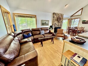 A cozy living room with a brown leather sectional sofa, a wooden coffee table, and a stone accent wall.