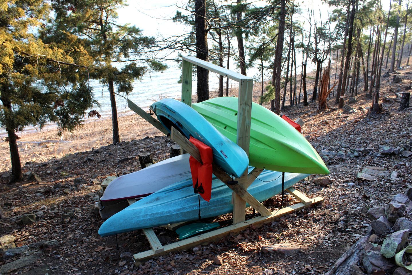 A wooden rack holding several kayaks and a paddleboard.