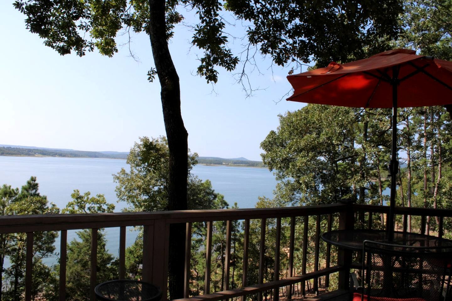 A deck with a view of a lake, surrounded by trees.