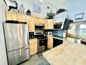 A modern kitchen with stainless steel appliances, wooden cabinets, and a large island.