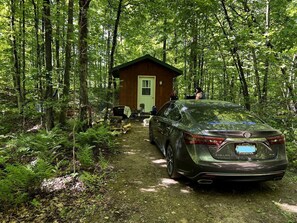 A car parked in a forested area with a small cabin in the background. - Romantic Cabin for a Cozy Escape in Nature near White Lake, Wisconsin (White Lake)