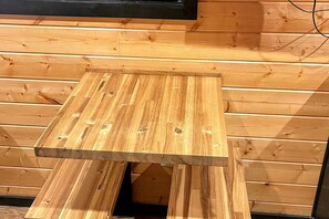 A wooden table with a black top, positioned against a wooden wall with horizontal planks.