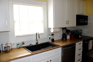 Una cocina equipada con un lavaplatos, estufa, microondas y alacenas.