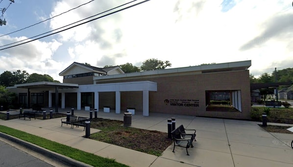A building with a sign reading 'VISITOR CENTER' and a covered outdoor area with benches.