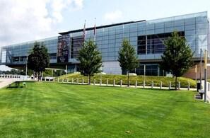 A modern building with a glass facade, a well-maintained lawn, and a few trees.