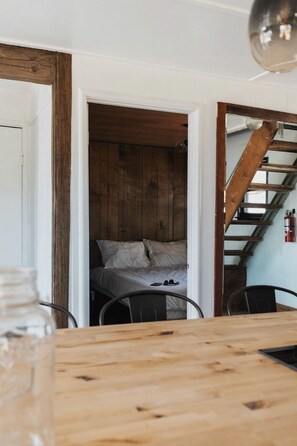 Een kamer met een bed, een houten tafel en een trap.