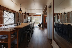A kitchen with a wooden bar, bar stools, and a view to the outside. - Secluded and Rustic Three Bedroom Cabin with Wood Burning Stove, Perfect for a Glamping Retreat in the Sequoias (Dunlap)