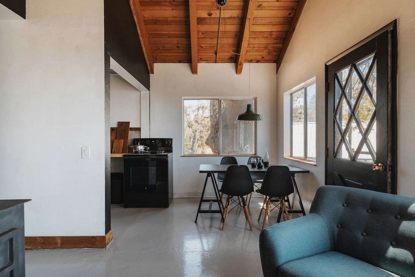 A spacious kitchen with a dining area, wooden ceiling beams, and a large window providing natural light.