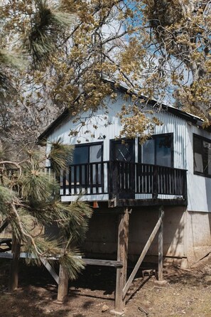 A single-story building with a balcony, surrounded by trees. - Secluded and Minimalist One Bedroom Cabin, Perfect for a Visit to Kings Canyon National Park (Dunlap)
