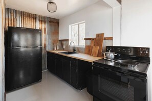 A modern kitchen with black appliances, a wooden countertop, and a window providing natural light. - Secluded and Minimalist One Bedroom Cabin, Perfect for a Visit to Kings Canyon National Park (Dunlap)