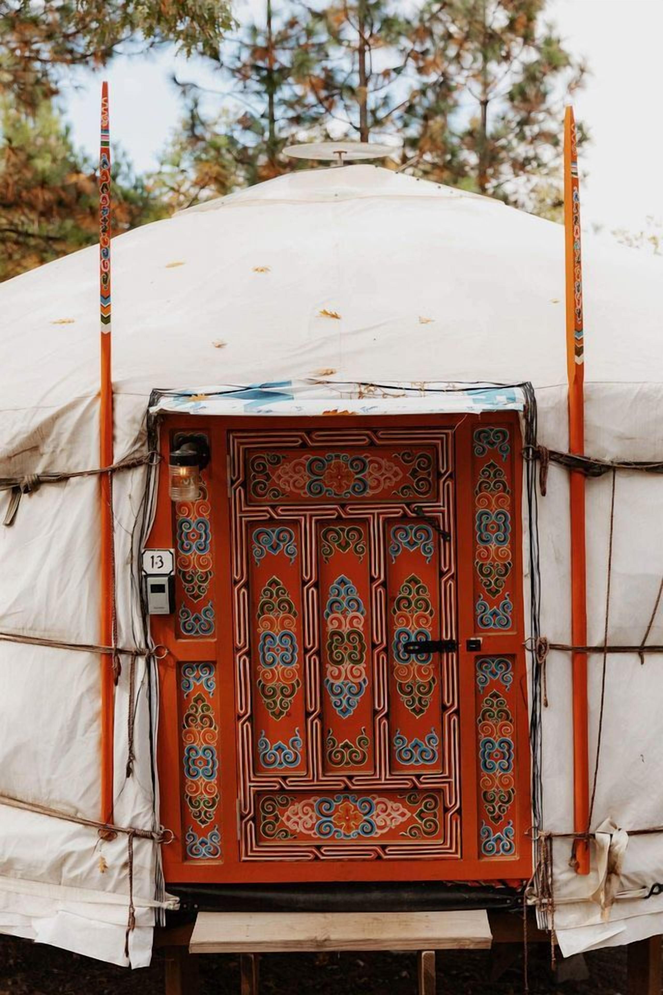 A tent with a decorative door, number 13, and a view of trees in the background.