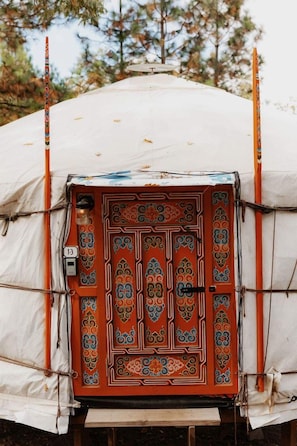 A tent with a decorative door, number 13, and a view of trees in the background.