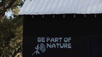 A building with a corrugated metal roof and a sign that reads 'BE PART OF NATURE.'