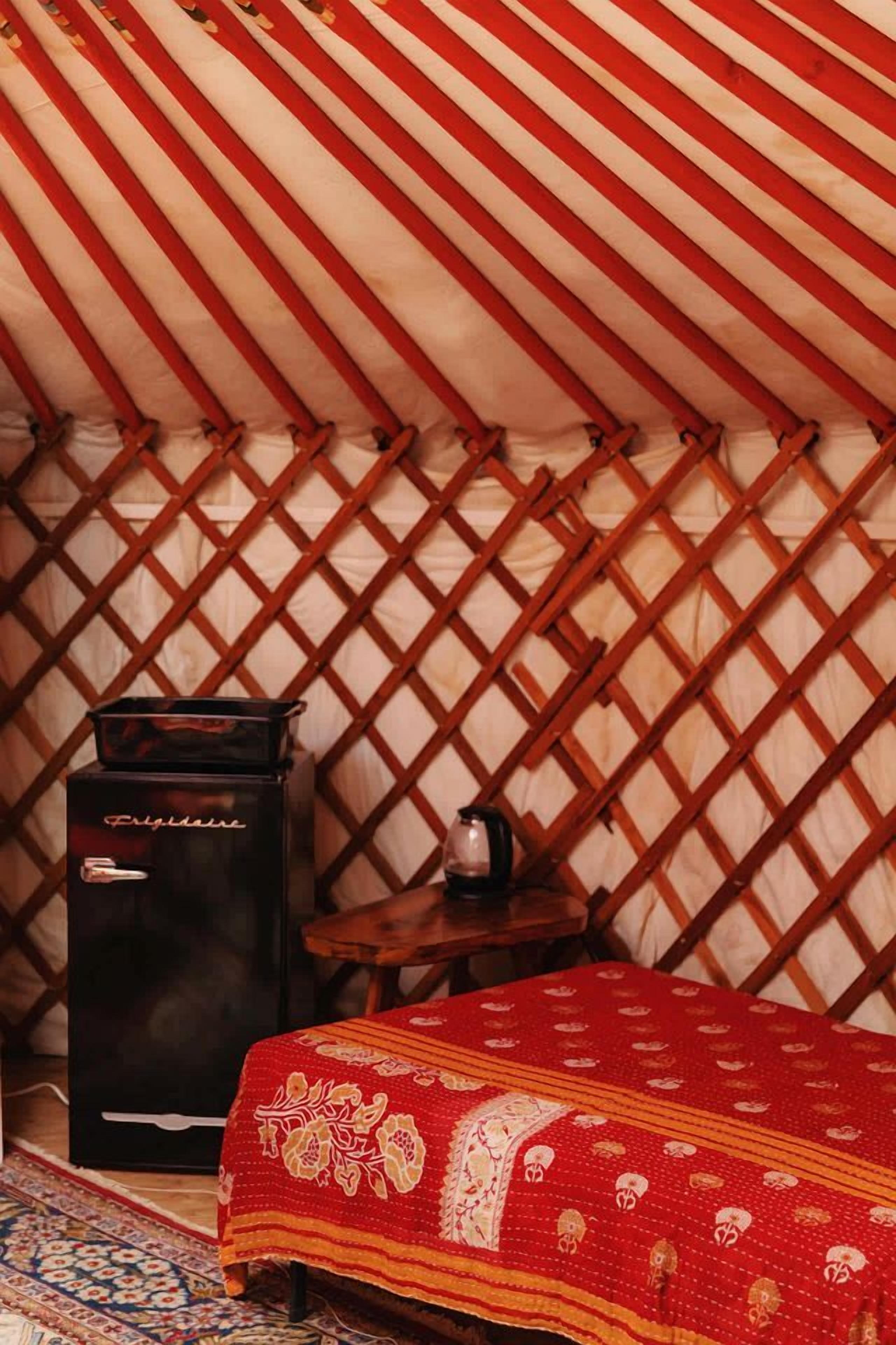 A tent interior with a bed, a heater, and a small table.