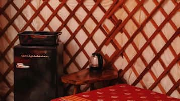 A tent interior with a bed, a heater, and a small table.