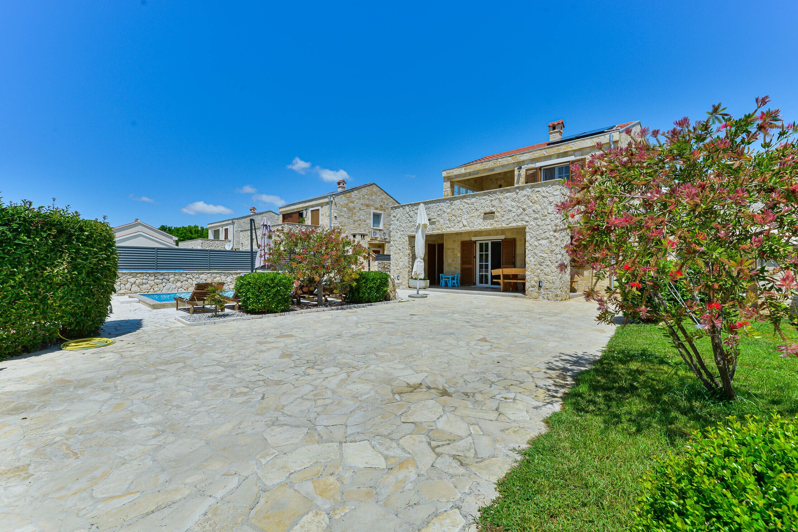 A stone-paved courtyard with a pool, stone buildings, and lush greenery.
