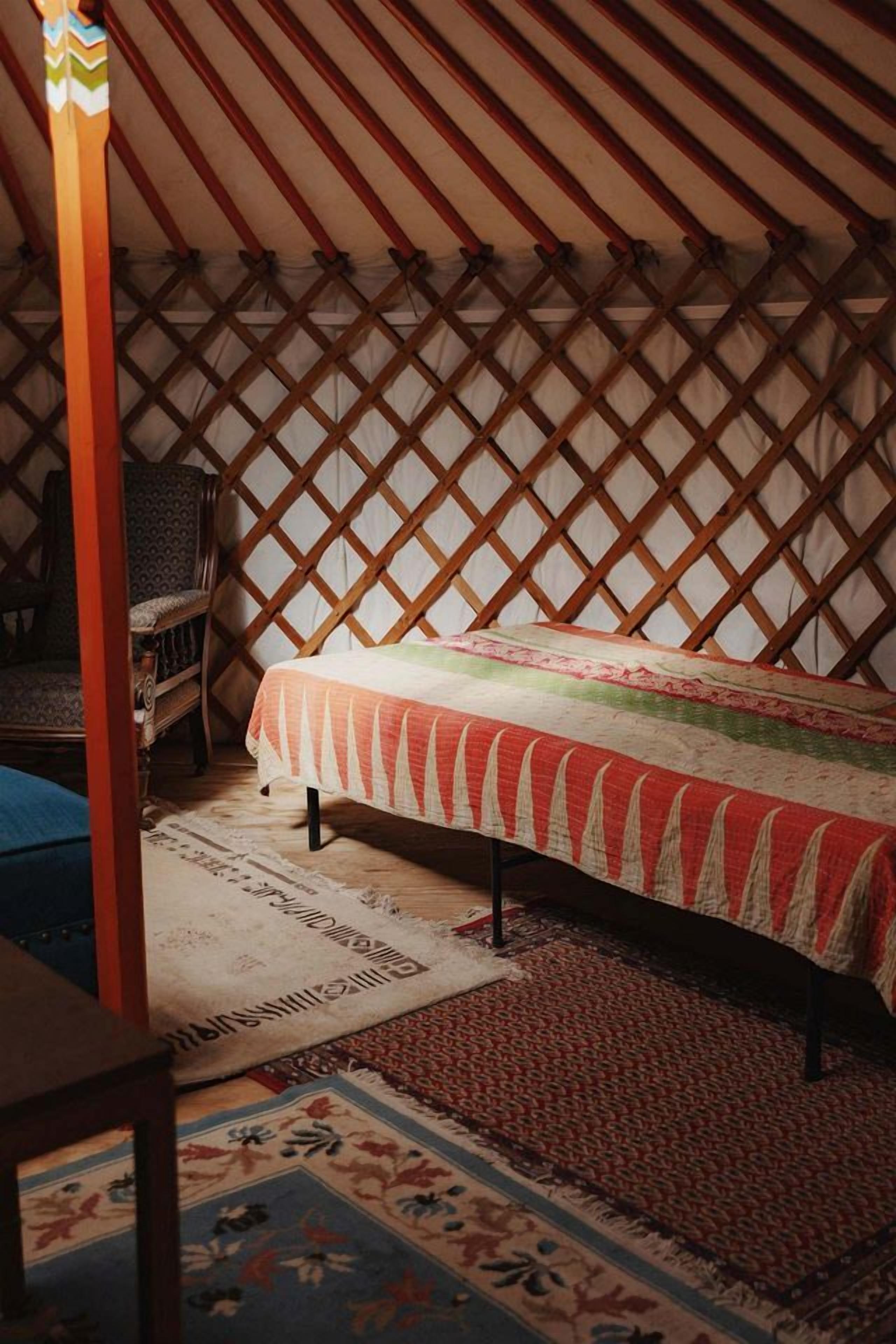 A room with a bed, a chair, and a wooden lattice wall.