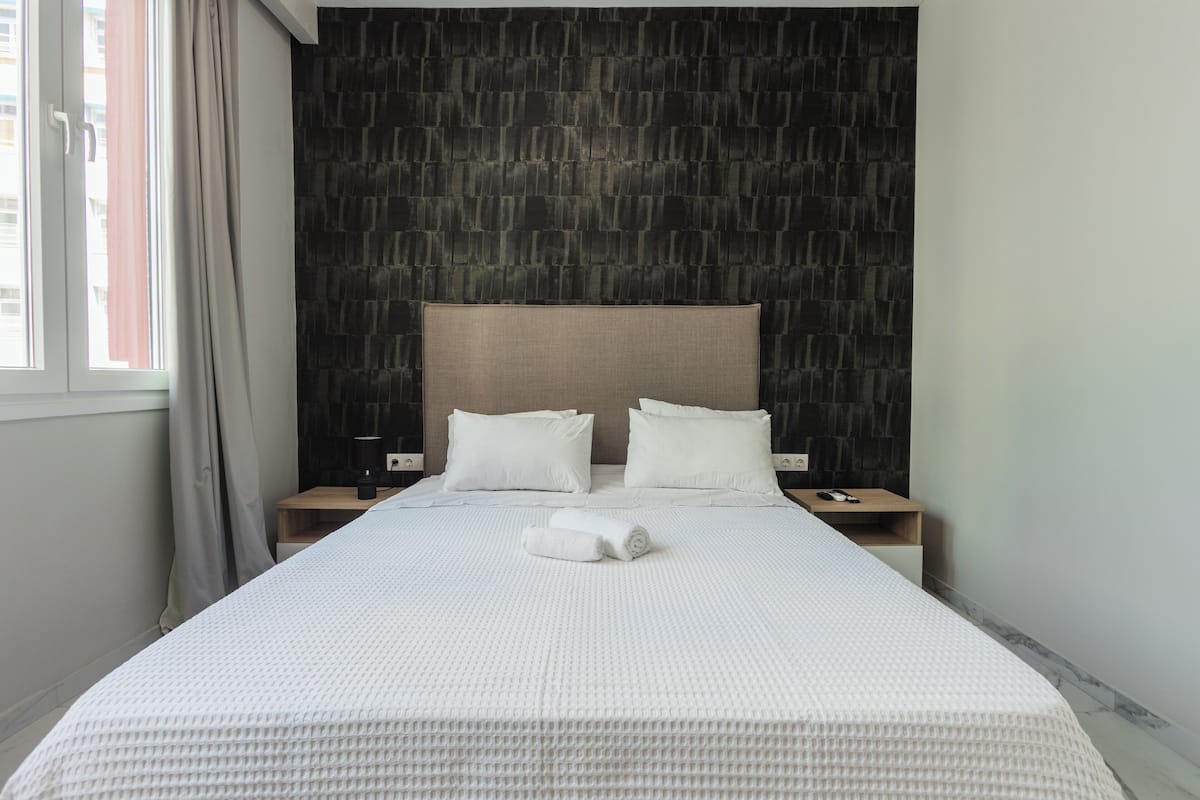 A neatly made bed with white bedding, a headboard, and two bedside tables with lamps.