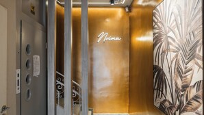 A modern hotel lobby with a marble floor, a wooden reception desk, a wall-mounted artwork, and a neon sign. - Noima Luxury Suites (Thessaloniki)