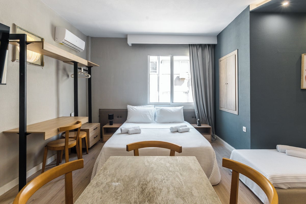 A hotel room with a bed, a desk, a chair, and a window with curtains.