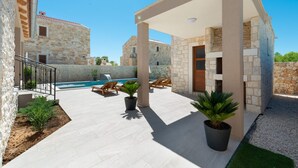 A stone building with a pool, lounge chairs, and potted plants. - Villa Rea 3 with heated pool (Privlaka)