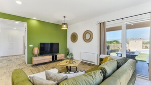 A modern living room with a green accent wall, a flat-screen TV, a wooden coffee table, and a large green sofa. - Villa Rea 4 with heated pool (Privlaka)