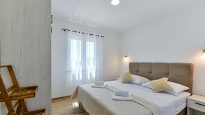 A neatly arranged bedroom with a bed, bedside tables, and a window with curtains. - Villa Rea 4 with heated pool (Privlaka)