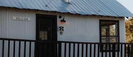 A building with a corrugated metal roof, a black door, and a sign that reads 'DELIHAM.'